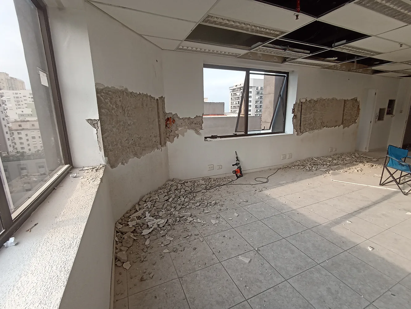Revestimento removido em parede de sala comercial durante investigação de patologia